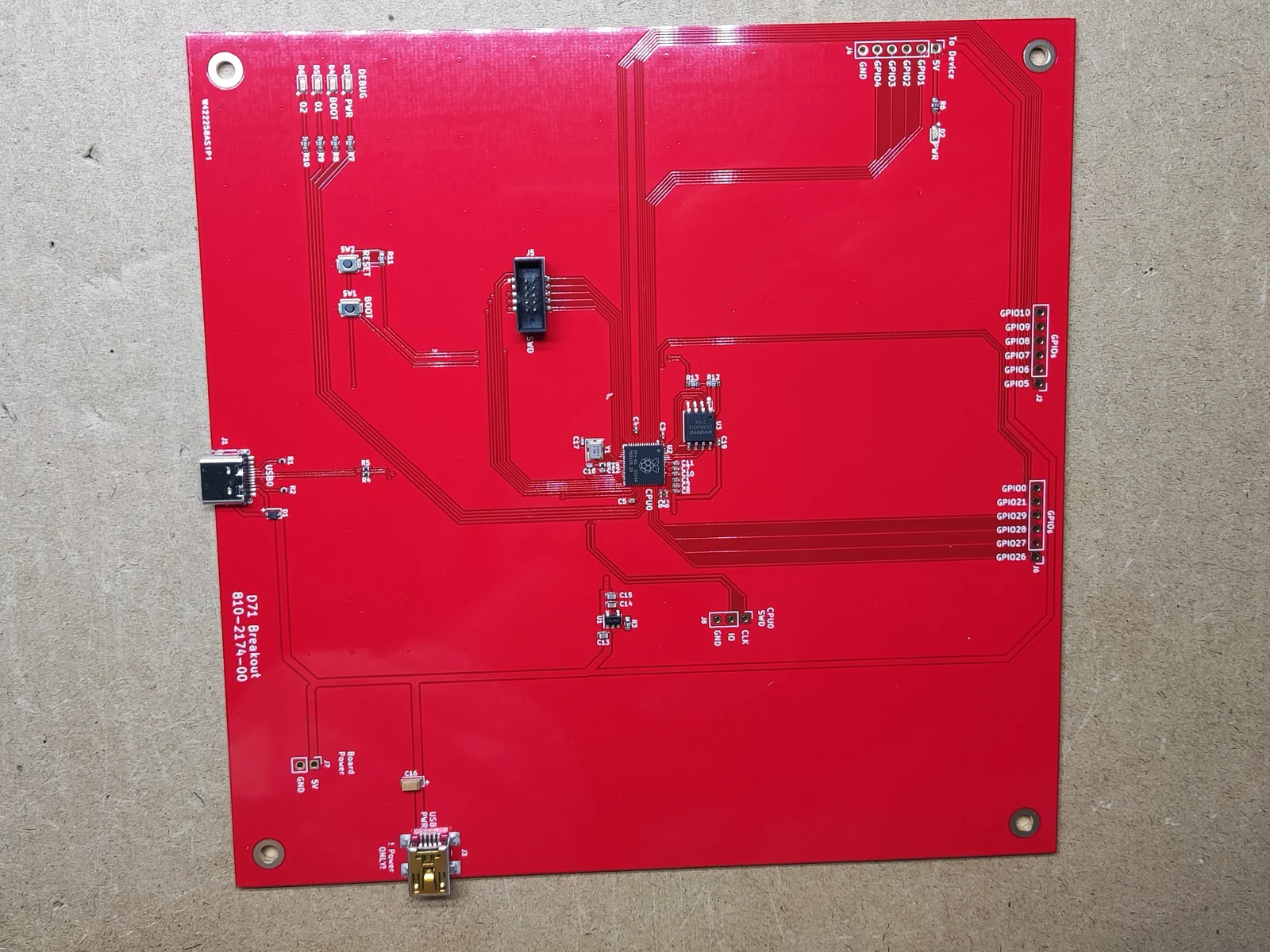 A populated red D71 Breakout board photographed on a bench, with the RP2040, a USB-C port, an SWD header and rows of labelled GPIO breakouts.