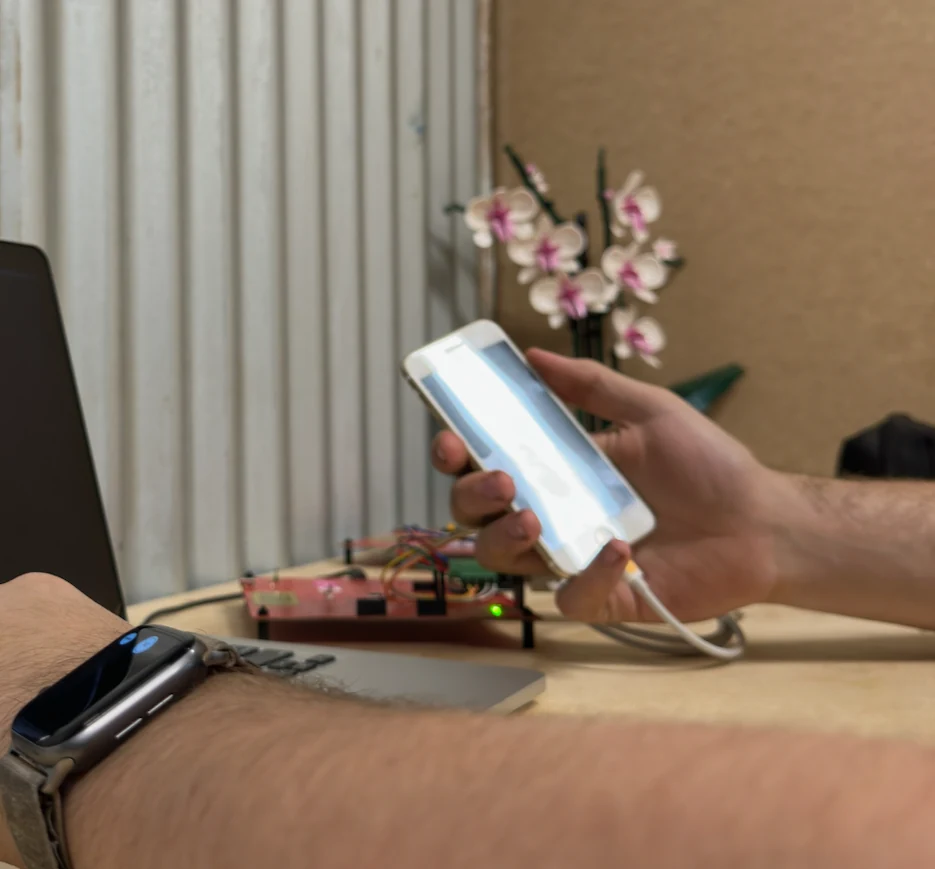 An early Helix board wired up on a bench, connected by a Lightning cable to an iPhone held in hand.